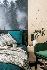 a bedroom with a bed and a green chair at Black River Apartment in Czarny Dunajec