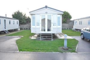 a small white camp house in a parking lot at Caravan by Camber Sands in Camber