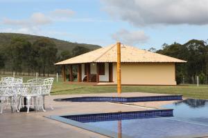 um pavilhão com uma mesa e cadeiras ao lado de uma piscina em Estancia Jacy em Alto Paraíso de Goiás