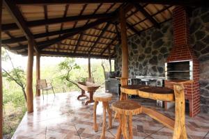 an outdoor kitchen with a stone fireplace and stools at Estancia Jacy in Alto Paraíso de Goiás