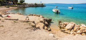 a beach with rocks and a boat in the water at Korina Apartments Mandre in Mandre