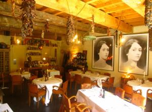 a restaurant with tables and chairs and portraits of women at Hotel Les Templiers in Aigues-Mortes