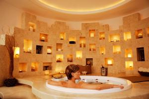 a woman sitting in a bath tub next to a large mirror at Krystal Cancun in Cancún