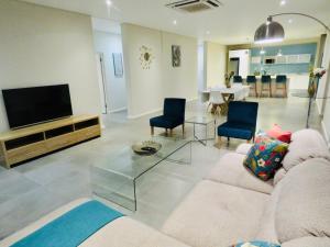 uma sala de estar com um sofá e uma televisão de ecrã plano em The Executive - Exclusive Self-Catering Apartments - Ezulwini em Ezulwini