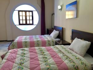 a bedroom with two beds and a large window at Sunflower Guest House Luxor West Bank in Luxor