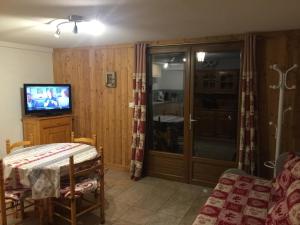 a living room with a tv and a table and a television at L'étable in Crévoux