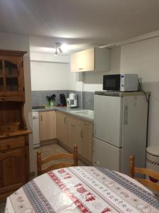 a small kitchen with a white refrigerator and a table at L'étable in Crévoux