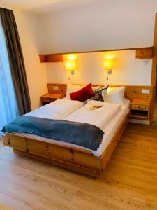 a bedroom with a large bed with white sheets and red pillows at Gasthof Schöntal in Werfenweng