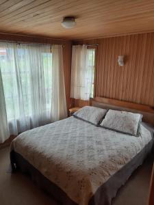 una camera da letto con letto, lenzuola bianche e finestre di Cabañas Don Foncho a Castro