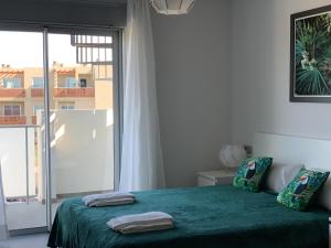 une chambre avec un lit vert avec une grande fenêtre dans l'établissement Apartamento Nuevo Terrazas, à Granadilla de Abona 30 autres photos