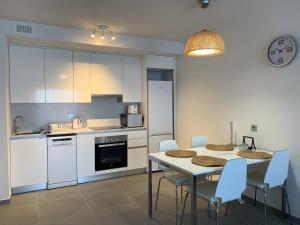 une cuisine avec des armoires blanches et une table et des chaises dans l'établissement Apartamento Nuevo Terrazas, à Granadilla de Abona