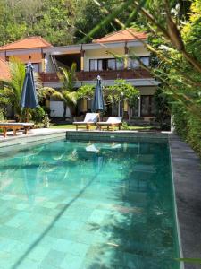 a swimming pool with umbrellas in front of a house at Crystal Bay Bungalows in Nusa Penida