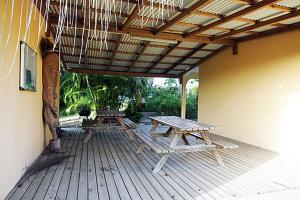 une terrasse en bois avec des tables de pique-nique et un toit. dans l'établissement BALAGA ocarina, à Sainte-Anne