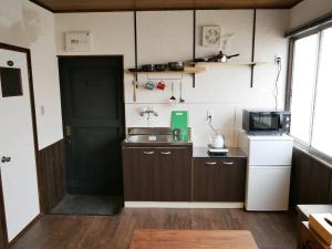 una pequeña cocina con fregadero y microondas en GUEST HOUSE KISHINOSATO, en Osaka