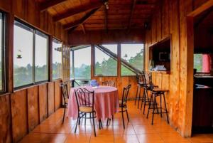 a dining room with a table and chairs and windows at Hotel Chalets Los Volcanes in Alajuela