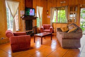 a living room with two chairs and a fireplace at Hotel Chalets Los Volcanes in Alajuela