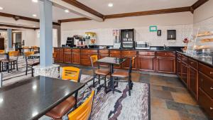 uma grande cozinha com armários de madeira, mesas e cadeiras em SureStay Hotel by Best Western Cedar Rapids em Cedar Rapids