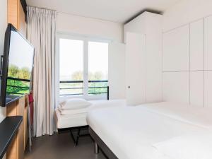 a bedroom with a white bed and white walls at ibis Budget Knokke in Knokke-Heist