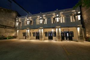 a large white building with lights on it at night at Macalister Terraces Hotel in George Town