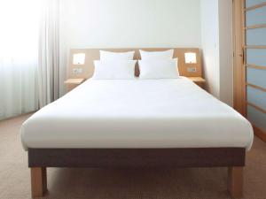1 cama con sábanas blancas y almohadas en una habitación en Novotel London Heathrow Airport M4 Jct. 4, en Hillingdon