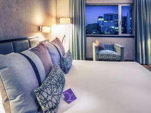 a hotel room with a bed, chair, and nightstand at Mercure Santiago Centro in Santiago