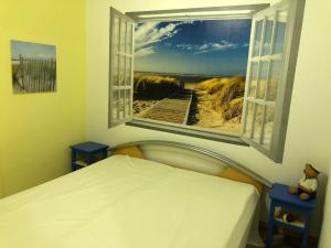 a bedroom with a bed and a window with a beach view at 50035.... in Altfunnixsiel