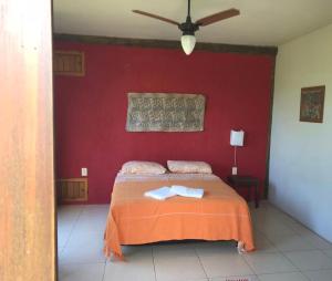 1 dormitorio con 1 cama con pared roja en Villa California, en Praia do Rosa