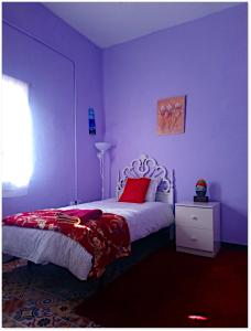 a bedroom with purple walls and a bed with red pillows at The Violet House muy cerca del Aeropuerto Tenerife Norte in Las Lagunas
