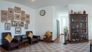 a living room with chairs and a clock on the wall at Sino Mansion in Ranong