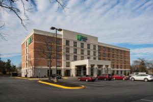 un gran edificio con coches estacionados en un estacionamiento en Holiday Inn Express & Suites Laurel Lakes, an IHG Hotel, en Laurel