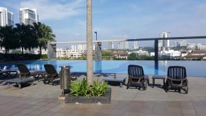 a group of chairs and tables next to a swimming pool at Residence @ Shaftsbury Cyberjaya in Cyberjaya