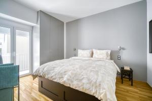 a white bedroom with a bed and a window at Bright Spacious Luxury Apartment in Prime Central Athens in Athens