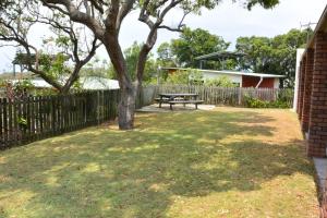 a bench in a yard with a fence and a tree at Alicante in Point Lookout