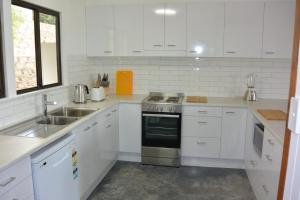 a white kitchen with a sink and a stove at Alicante in Point Lookout