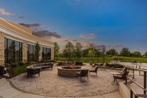 un patio avec des chaises et un foyer extérieur en face d'un bâtiment dans l'établissement Holiday Inn Hotel & Suites - Joliet Southwest, an IHG Hotel, à Joliet