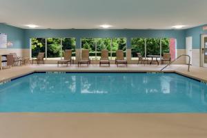 - une piscine dans une chambre d'hôtel avec des chaises et des tables dans l'établissement Holiday Inn Express Arrowood, an IHG Hotel, à Charlotte