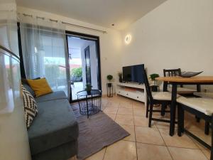 salon z kanapą, stołem i telewizorem w obiekcie Green Garden Gajac Apartman w mieście Skunca