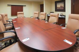 Staybridge Suites Guelph, an IHG Hotel في غيلف: قاعة اجتماعات مع طاولة وكراسي خشبية