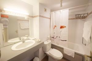 La salle de bains blanche est pourvue d'un lavabo et de toilettes. dans l'établissement Logis Hôtel L'Auzeraie, à Ax-les-Thermes