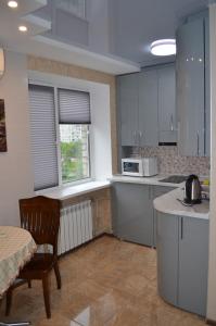 eine Küche mit weißen Schränken, einem Tisch und einem Stuhl in der Unterkunft 1-комнатная на левом берегу Днепра in Dnipro + 5 Fotos