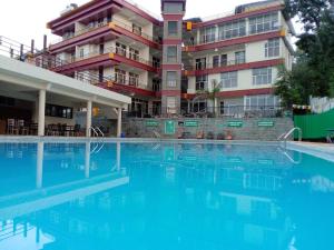 a large swimming pool in front of a building at Highland Village Resort in Dharmsāla