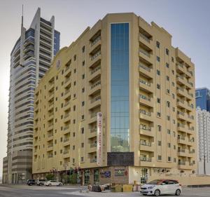 a large building with cars parked in a parking lot at Ramee Palace Hotel in Manama