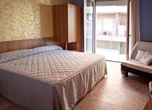 a bedroom with a bed and a chair and a window at La Lanterna in Silvi Marina
