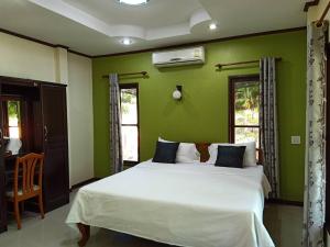 1 dormitorio con cama blanca y paredes verdes en Saithong Resort, en Udon Thani