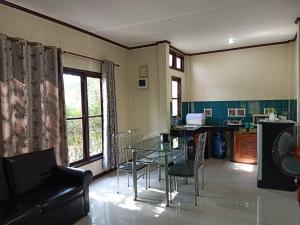 Saithong Resort في أودون ثاني: غرفة معيشة مع طاولة وكراسي زجاجية