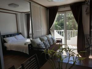 ein Schlafzimmer mit einem Bett und einem großen Fenster in der Unterkunft Gab's CozyHome at Bonbel Condo, Botanical Gardens Baguio in Baguio City