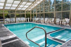 - une piscine avec des tables et des chaises dans un bâtiment dans l'établissement Holiday Inn Express Hotel & Suites North Conway, an IHG Hotel, à North Conway