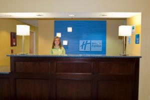 Holiday Inn Express Hotel & Suites North Conway, an IHG Hotel في نورث كونويه: امرأة تقف خلف منصة في غرفة فندق