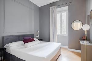 una camera da letto con un grande letto bianco e uno specchio di Suites by Chloe a Roma