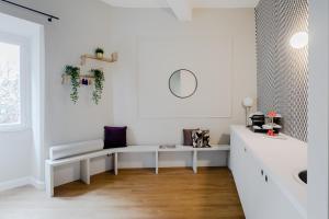 Una habitación blanca con un banco y un espejo. en Suites by Chloe, en Roma